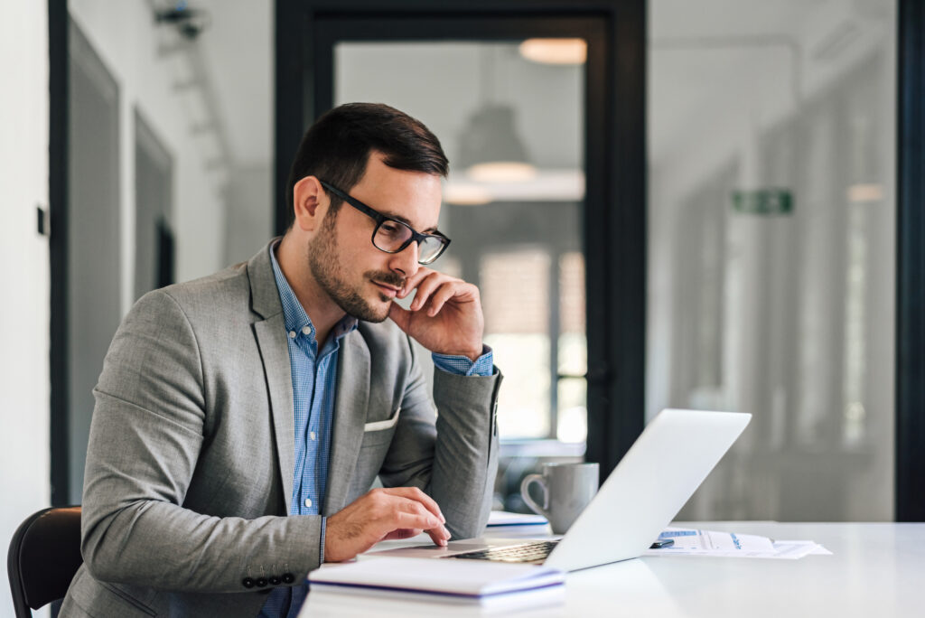 Profissional corporativo em um escritório sentado à mesa com um notebook